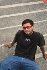 Remera blanca de manga corta con cuello redondo y estampado de tres hongos rojos y la palabra "Tuya" en el frente.