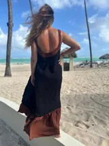 Vestido largo de fibrana, con corpiño negro ajustado y escote pronunciado en la espalda con tirantes anchos marrones. La falda es larga y voluminosa, con un ruedo ancho de tela marrón.