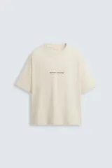 Camiseta color crema de corte cuadrado, con cuello redondo y mangas cortas. Estampado frontal con la frase "no matter what day" en letras pequeñas de color negro.