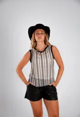 Blusa sin mangas de crochet calado en blanco y negro, con cuello redondo y ribete negro en sisas y cuello.