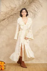 Vestido largo color crema con bordados florales en tonos pastel, escote en V con volados, mangas largas acampanadas y abertura frontal. Incluye lazo ajustable en la cintura.