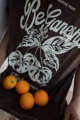 Remera marrón de corte amplio con estampado de texto y dibujo en color blanco.