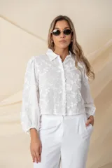 Camisa/chaqueta blanca de algodón con bordado floral en hilo de seda al tono, manga ancha terminada en frunce y botones forrados.