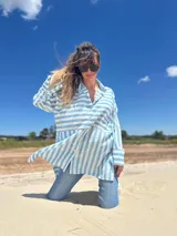 Camisa oversize celeste con rayas verticales blancas, de manga larga y cuello clásico.