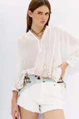 Camisa blanca de algodón con cuello mao y mangas largas. Presenta bordados calados en el ruedo.