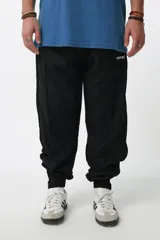 Pantalón de jogging negro de nylon con forro interno de red, corte recto, bolsillos laterales con cierre, cierres en los tobillos y cintura elástica con cordón ajustable.