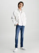 Jeans de denim elástico azul con efecto lavado, corte skinny, tiro bajo, cinco bolsillos y cierre con cremallera.