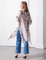 Kimono tejido con estampado abstracto en tonos beige, blanco y negro. Tiene mangas amplias estilo japonés y terminación de ruedo con borlas.