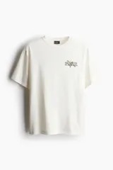 Remera color crema de corte holgado con estampado de flores y texto en el pecho.
