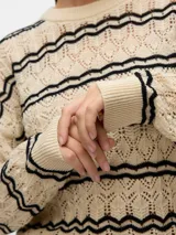 Sweater tejido color crema con rayas horizontales negras, cuello redondo y mangas largas.