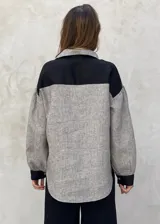 Camisa beige a rayas verticales finas, con cuello clásico, mangas largas abullonadas con puños marrones y cierre frontal con botones.