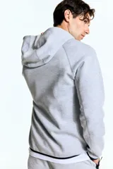 Campera deportiva gris con capucha, cierre frontal y bolsillos laterales con cierre. Confeccionada en tejido funcional DryMove™ que ayuda a absorber el sudor.
