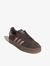 Zapatillas Adidas modelo Sambae, color marrón con detalles en rosa. Confeccionadas en cuero con refuerzos texturizados en la puntera y cordones. Suela de caucho color caramelo con dibujo multidireccional.