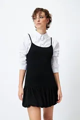 Vestido corto de lurex plateado y negro, sin mangas, con breteles finos regulables y volados tipo balloon desde la cadera.