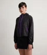 Campera cropped con capucha, de poliéster color negro con estampado de cuadros y salpicaduras de colores. Tiene cordón de ajuste en la capucha, elástico en puños y ruedo, bolsillos con cremallera y cierre frontal con cremallera.