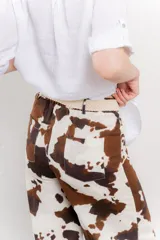 Pantalón ancho de lino con estampado de manchas de vaca en tonos marrón y blanco. Incluye cinturón de soga trenzada con flecos.
