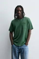 Camiseta verde oscuro de corte relaxed fit, cuello redondo, manga corta y bolsillo plastrón en el pecho.
