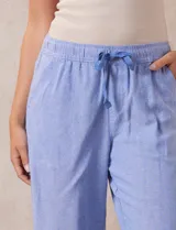 Pantalón largo de lino y rayón a rayas verticales grises y blancas. Tiene pretina elastizada con lazo de ajuste, bolsillos delanteros y traseros.