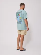 Remera de algodón color celeste pálido, corte oversize, con cuello redondo y manga corta. Presenta un pequeño estampado en el pecho con el texto "RUSTY MANTRA".