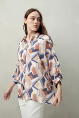 Camisa estampada con figuras geométricas en tonos azul, marrón y beige. Corte relajado, manga tres cuartos y botones al frente.
