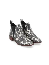 Botín Chelsea de cuero con estampado animal print en blanco y negro, elásticos laterales texturizados, punta semi-redondeada y taco bajo de madera.