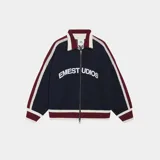 Campera azul con cuello tipo polo, cierre frontal con cremallera, corte oversize, puños y ruedo acanalados en color bordó y blanco. Presenta el logo de la marca bordado en el pecho y la inscripción "Emest Studios" en el frente.