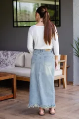 Pollera larga de jean de tiro alto, con detalle de flecos en la parte inferior y tajo frontal.