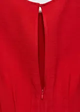 Vestido midi rojo sin mangas, con cuello redondo y corte evasé. Presenta pinzas en la cintura y cierre de cremallera y botón en la parte posterior.