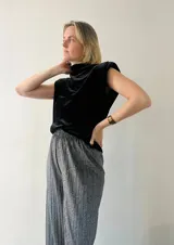 Blusa sin mangas de terciopelo negro con cuello alto y hombreras.