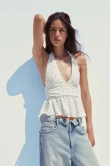 Top negro de cuello halter y escote pico con volantes en el bajo.
