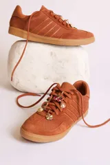 Zapatillas bajas de gamuza celeste con cordones y pañuelos estampados atados a los cordones.