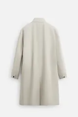 Gabardina color beige de corte relaxed fit, confeccionada en tejido italiano repelente al agua. Tiene cuello solapa, manga larga con puños abotonados, bolsillos de vivo en la cadera, bolsillo interior y abertura en la espalda.