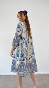 Vestido camisero de manga larga, color blanco con estampado azul de motivos marinos como medusas, conchas y corales. Tiene cuello camisero y bolsillos laterales.