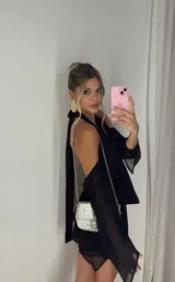 Minivestido negro con escote halter pronunciado y mangas largas con hombros descubiertos.