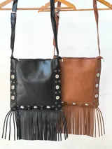 Cartera marrón con flecos y tachas plateadas, con correa larga al hombro.