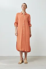 Vestido camisero midi color durazno, de lino, con cuello camisero, abotonado al frente y mangas largas con trabillas.