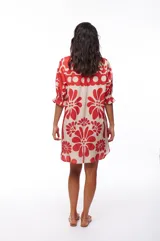 Vestido corto tipo camisero con botones al frente y mangas cortas con elástico y volado. Estampado con flores rojas y beige.