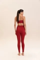 Conjunto deportivo color borgoña, compuesto por un top deportivo de tirantes finos y calzas de compresión media, sin costuras, de textura suave y alta transpirabilidad.