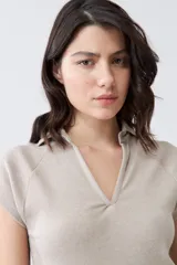 Remera de punto canalé color beige melange, con cuello polo y mangas cortas.