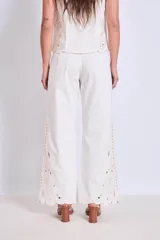Pantalón blanco de corte ancho con bordados calados en forma de hojas en el ruedo.