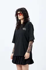 Remera blanca de corte holgado con mangas cortas y cuello redondo. Estampado pequeño en el frente con la frase "Spritz and Shine" en verde.