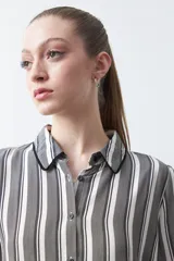 Camisa de manga larga color marrón con estampado de lunares blancos, confeccionada en tejido liviano con cuello clásico y botones frontales.