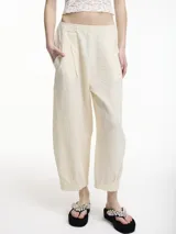 Pantalón tipo chino color crudo, con bolsillos laterales y pretina elástica. Textura arrugada.