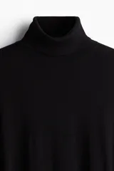 Polera negra de punto fino, cuello alto, corte ajustado y mangas largas.