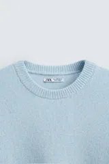 Sweater celeste de punto con cuello redondo y manga larga.