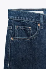Pantalón de jean azul oscuro, de corte wide leg y tiro medio, con cinco bolsillos y cierre frontal con cremallera y botón metálico.