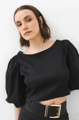 Falda larga negra de tafeta con cintura ajustada, tajo lateral y volados escalonados.