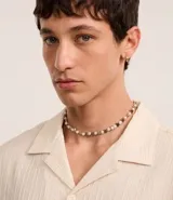 Collar corto de perlas artificiales blancas alternadas con dijes de estrellas plateadas.