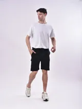 Bermuda color gris con cintura elástica ajustable con cordón, bolsillos laterales y un bolsillo tipo cargo en la pierna izquierda.