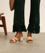 Sandalia mule color beige con puntera redonda, tira ancha en forma de H con efecto ráfia y tacón bloque mediano.